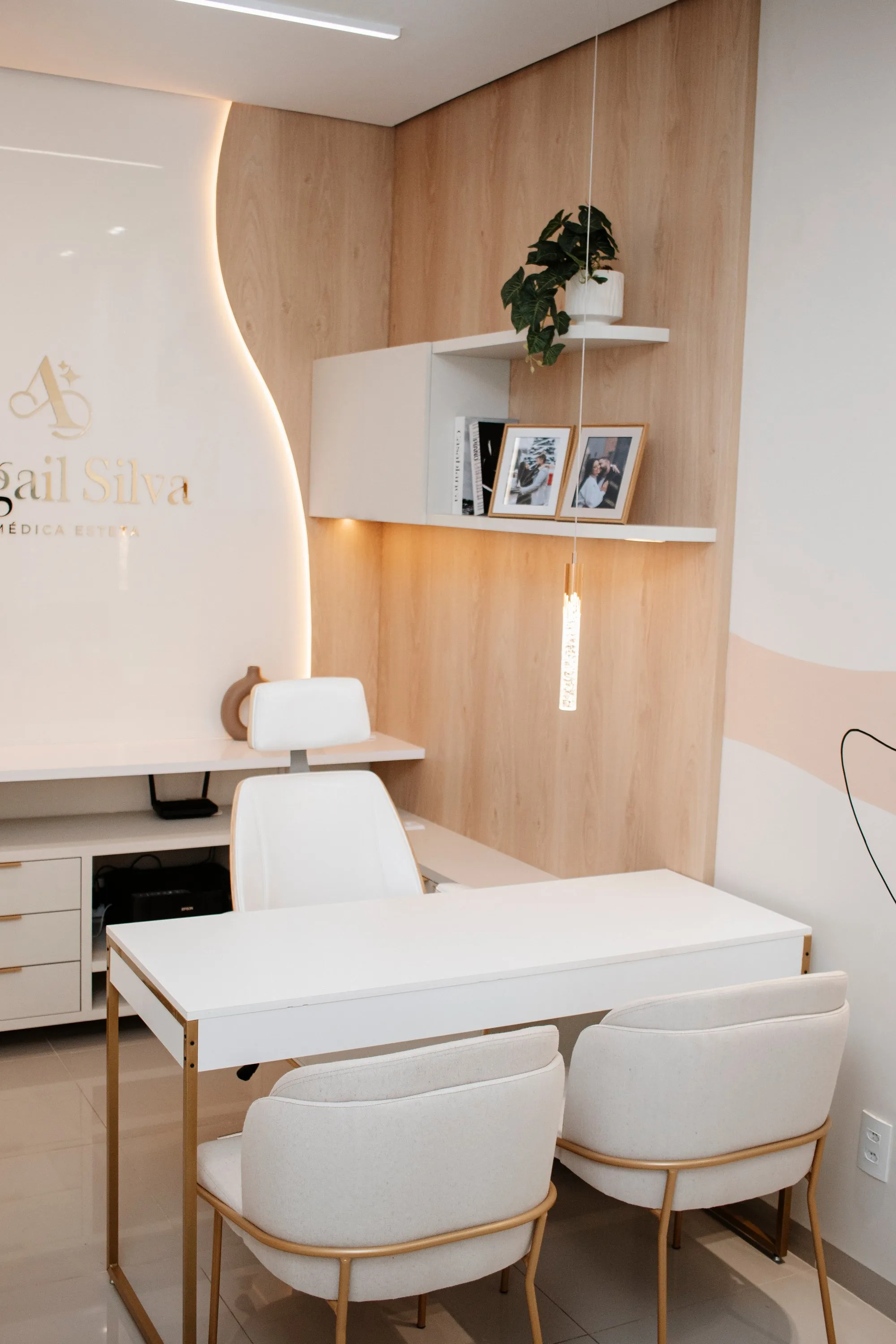 Consultório da clínica, com mesa de atendimento e a marca Abigail Silva na parede